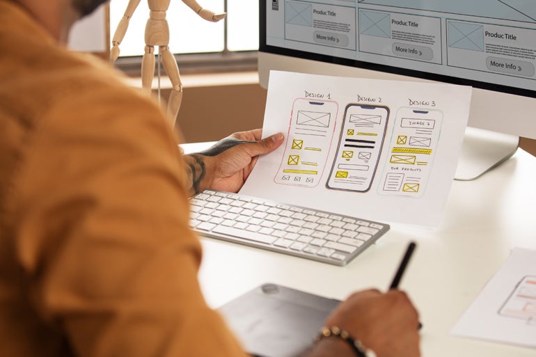 Man working on a design on his computer from a mock up.